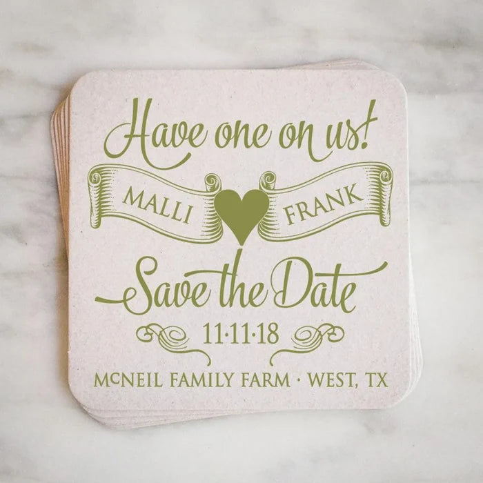 A white coaster with a green and gold design that says "Have one on us! Malli & Frank Save the Date 11-11-18 McNeill Family Farm - West, TX"