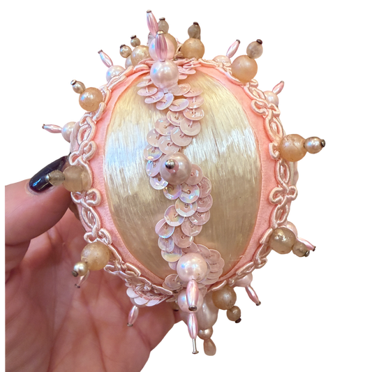 handmade vintage Christmas ornament featuring ivory satin, blush pink pearl embellishments, delicate gold trim, and dangling pink beads.
