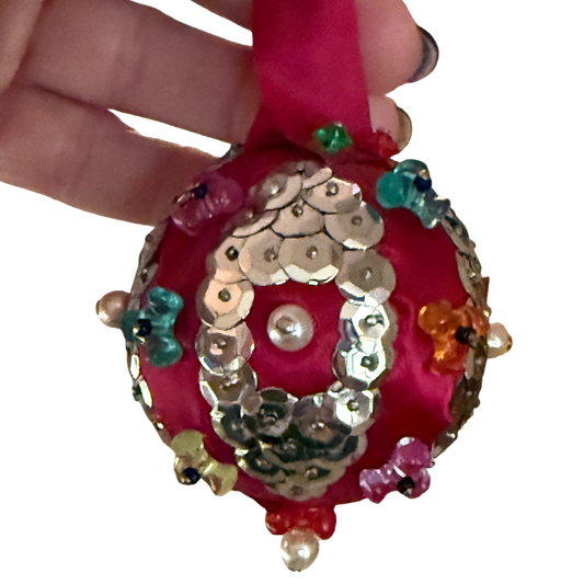 Vintage red satin ornament with oval silver sequin medallions, pearl-look centers, colorful translucent beads, and a red ribbon hanging loop.